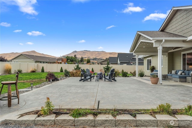 view of patio / terrace featuring a mountain view, an outdoor living space with a fire pit, and a fenced backyard