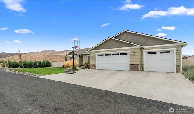 ranch-style home featuring driveway, a front lawn, stone siding, a garage, and a mountain view