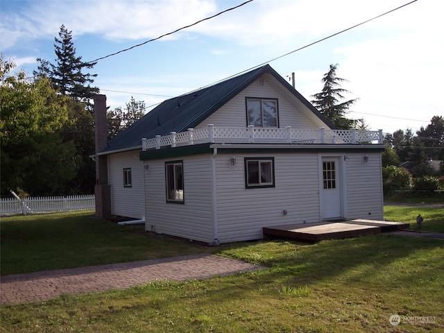 back of house featuring a lawn and a deck