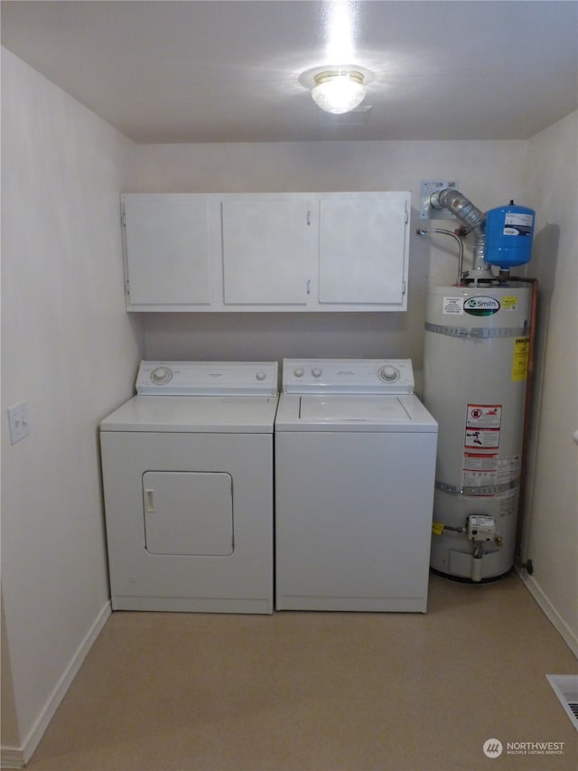 clothes washing area with cabinets, water heater, and washing machine and clothes dryer