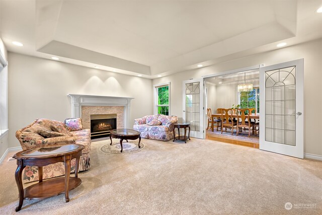 carpeted living room with a tray ceiling and a fireplace