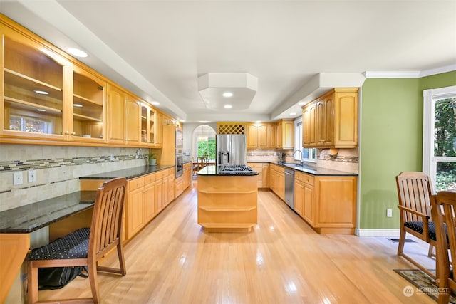 kitchen with a center island, tasteful backsplash, sink, light hardwood / wood-style flooring, and appliances with stainless steel finishes