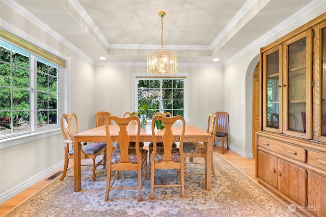 dining space featuring a raised ceiling, crown molding, and light hardwood / wood-style floors