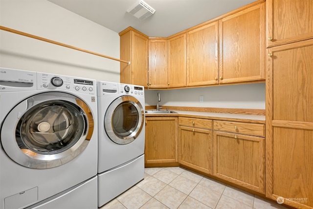 washroom featuring independent washer and dryer, sink, light tile patterned floors, and cabinets