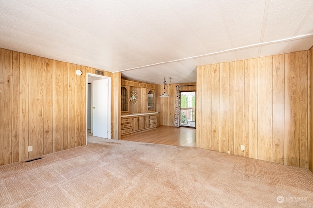 unfurnished living room featuring light carpet and wooden walls