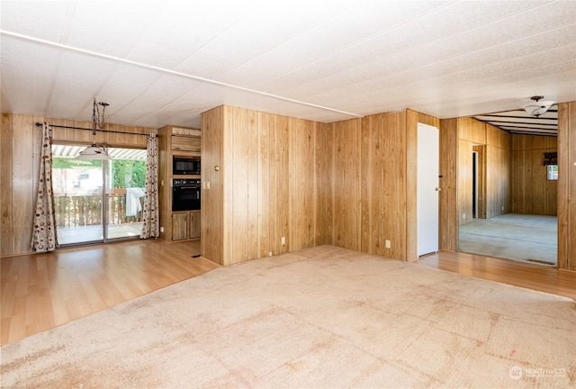 unfurnished room featuring ceiling fan, hardwood / wood-style flooring, and wood walls