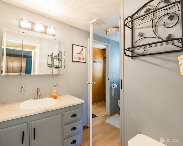 bathroom featuring vanity, hardwood / wood-style floors, toilet, and a textured ceiling