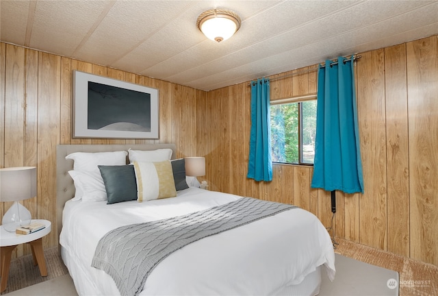 carpeted bedroom with a textured ceiling and wood walls