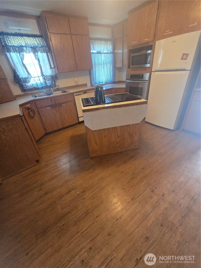 kitchen with appliances with stainless steel finishes, a kitchen island, a sink, and dark wood-style floors