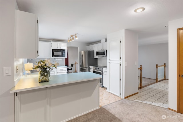 kitchen featuring white cabinetry, backsplash, kitchen peninsula, stainless steel appliances, and light colored carpet