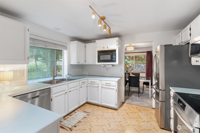 kitchen with sink, track lighting, stainless steel appliances, and white cabinets