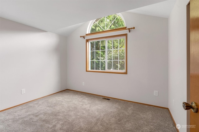 carpeted empty room featuring lofted ceiling