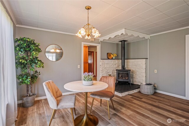 dining area featuring ornamental molding, an inviting chandelier, hardwood / wood-style floors, and a wood stove