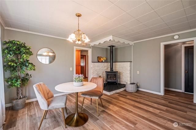 dining room featuring hardwood / wood-style flooring, crown molding, a notable chandelier, and a wood stove