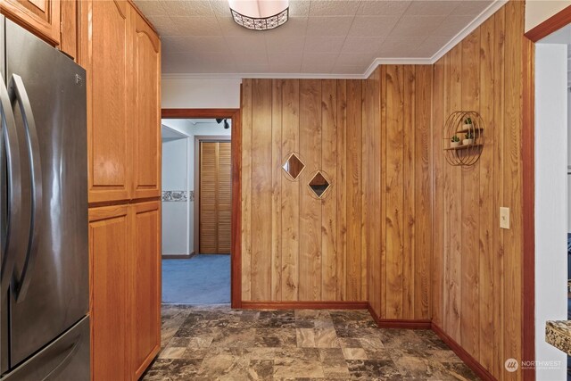 corridor featuring crown molding and wood walls