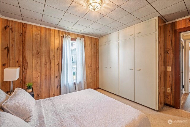 carpeted bedroom with wooden walls and a closet