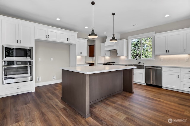 kitchen featuring decorative light fixtures, stainless steel appliances, dark wood-type flooring, and white cabinetry