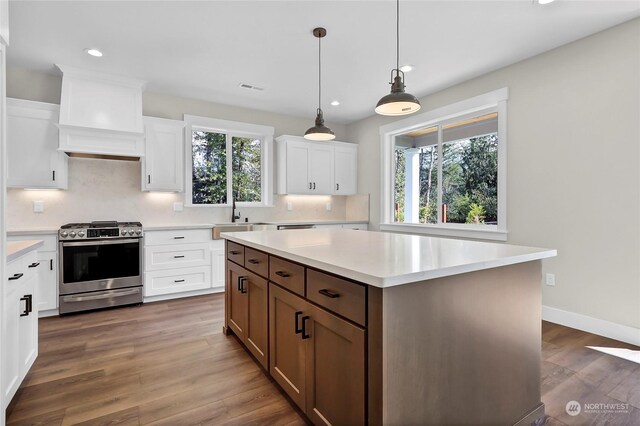 kitchen featuring stainless steel gas stove, white cabinets, a center island, and a healthy amount of sunlight