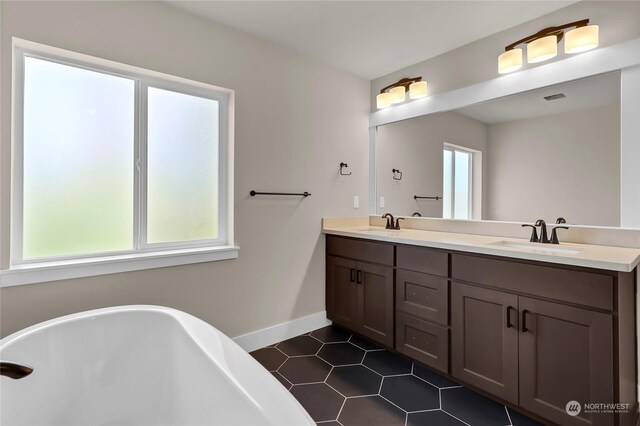 bathroom featuring tile patterned floors, vanity, and a washtub