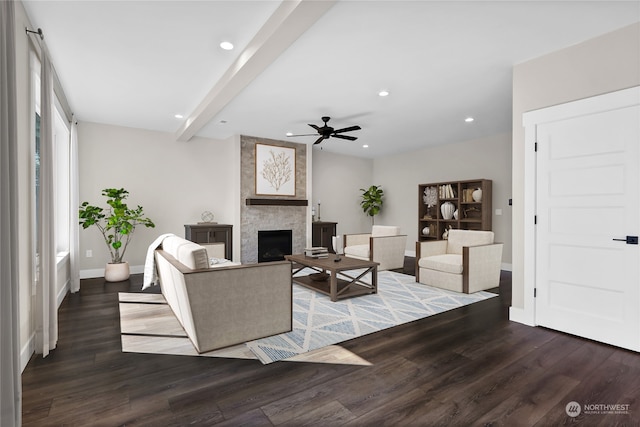 living room with ceiling fan, beamed ceiling, dark hardwood / wood-style flooring, and a stone fireplace