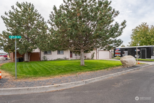 view of property hidden behind natural elements featuring a front yard and a garage