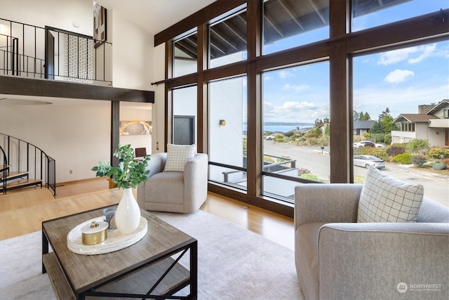 living room with light hardwood / wood-style floors, a water view, and high vaulted ceiling