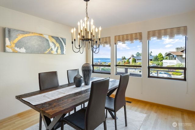 dining room with light wood-type flooring and a chandelier