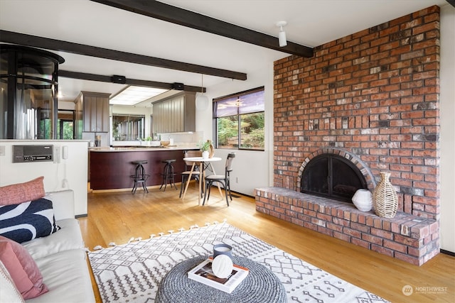 living room with a brick fireplace, light hardwood / wood-style floors, and beamed ceiling