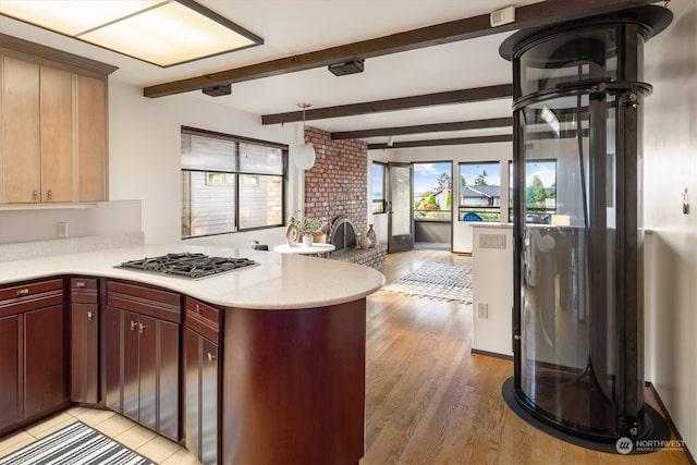 kitchen featuring light hardwood / wood-style floors, a fireplace, stainless steel gas cooktop, and kitchen peninsula