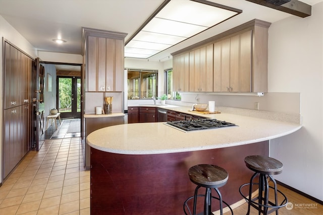 kitchen with sink, kitchen peninsula, a kitchen breakfast bar, appliances with stainless steel finishes, and light tile patterned floors