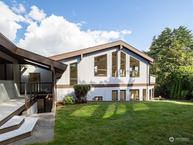 rear view of property with a yard and a wooden deck