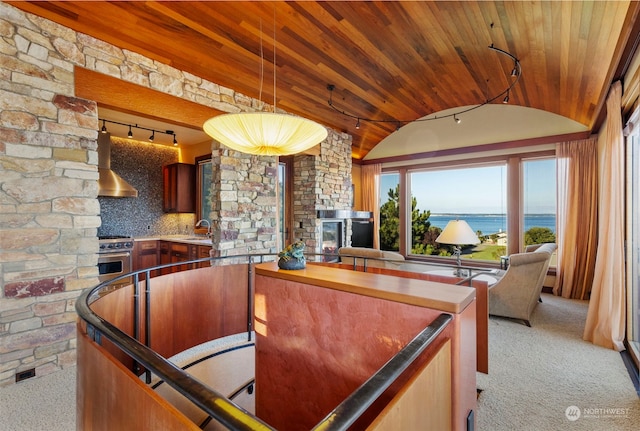 kitchen with tasteful backsplash, light colored carpet, wall chimney range hood, a water view, and high end range