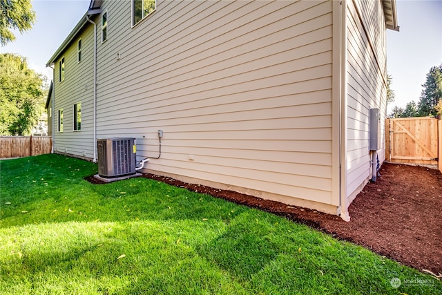 view of home's exterior with cooling unit and a yard