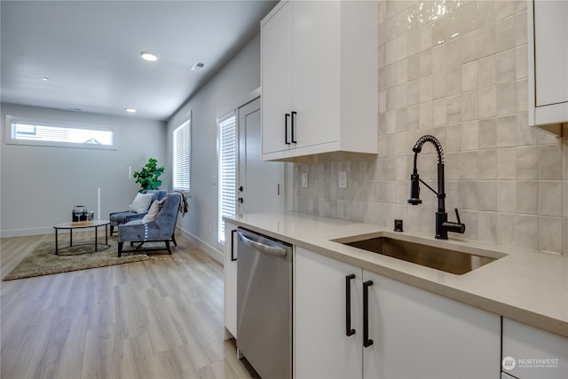 kitchen featuring white cabinets, dishwasher, light hardwood / wood-style floors, and sink