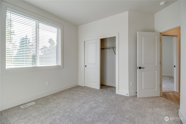 unfurnished bedroom with light colored carpet and a closet