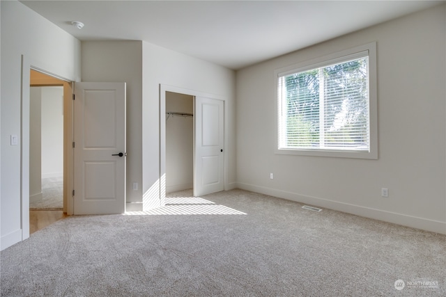 unfurnished bedroom with light colored carpet and a closet