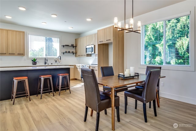 dining area with sink, a chandelier, and light hardwood / wood-style floors