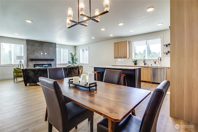 dining room with a large fireplace, a chandelier, light wood-type flooring, and sink