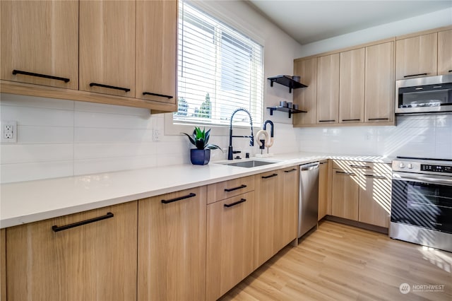 kitchen with backsplash, stainless steel appliances, light brown cabinetry, light hardwood / wood-style flooring, and sink