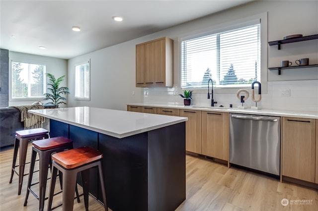 kitchen featuring sink, dishwasher, a center island, light wood-type flooring, and decorative backsplash