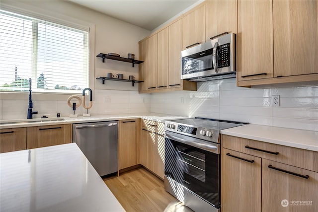 kitchen featuring appliances with stainless steel finishes, backsplash, light hardwood / wood-style floors, and light brown cabinetry