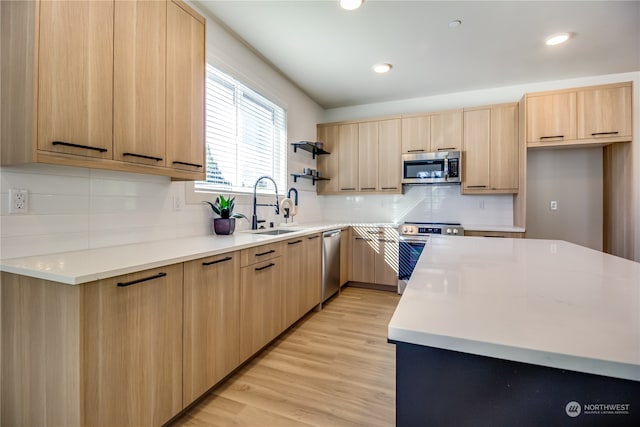 kitchen with appliances with stainless steel finishes, light wood-type flooring, light brown cabinetry, and sink