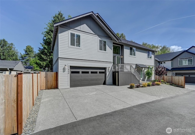 raised ranch featuring an attached garage, fence, and driveway