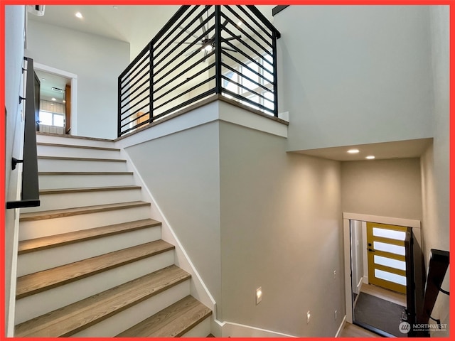 stairway featuring a towering ceiling