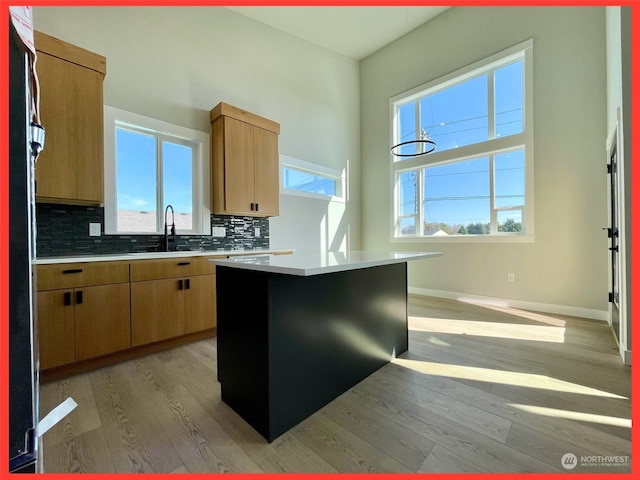 kitchen featuring a kitchen island, sink, decorative backsplash, and light hardwood / wood-style floors