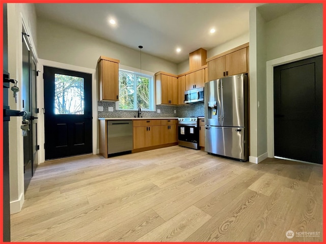 kitchen featuring appliances with stainless steel finishes, light hardwood / wood-style flooring, decorative backsplash, and hanging light fixtures