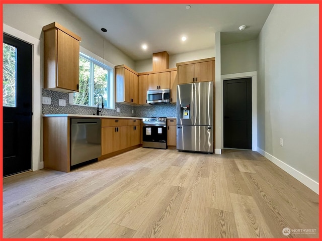 kitchen with decorative backsplash, light hardwood / wood-style flooring, stainless steel appliances, sink, and pendant lighting