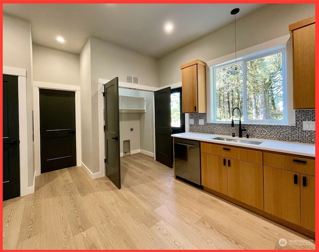 kitchen featuring stainless steel dishwasher, sink, light hardwood / wood-style flooring, and decorative backsplash