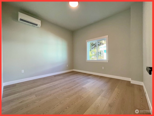 spare room featuring an AC wall unit and light wood-type flooring