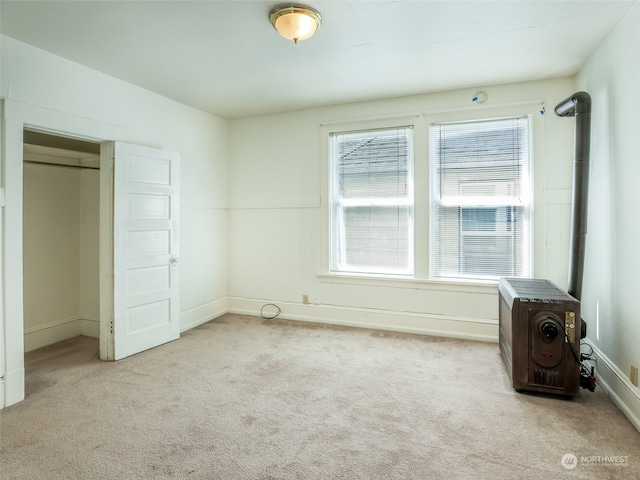 unfurnished bedroom featuring light carpet, a wood stove, and a closet